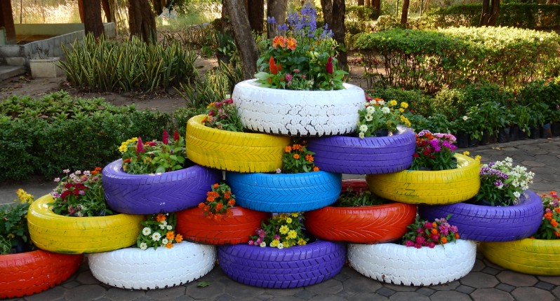Bild på däck uppbyggda som en mur målade i olika färger med växter i.